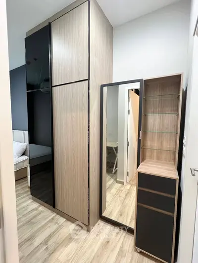 Modern bedroom with sleek wardrobe and mirror, showcasing stylish interior design.