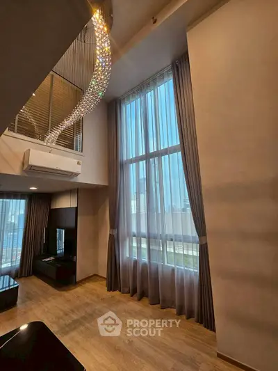 Luxurious high-ceiling living room with elegant chandelier and floor-to-ceiling windows.