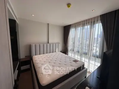 Spacious bedroom with large windows and modern furnishings, offering ample natural light and city views.