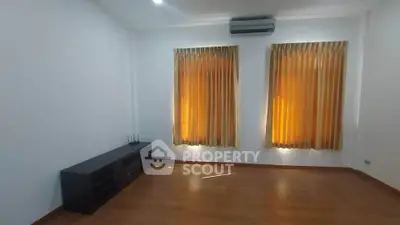 Spacious empty room with wooden flooring and large windows with curtains, ideal for customization.