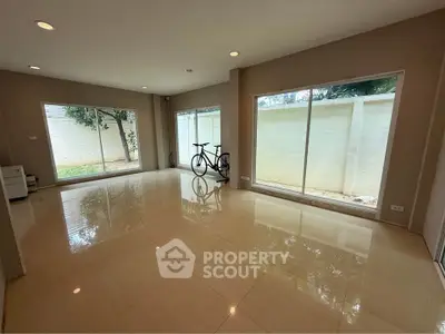 Spacious living room with large windows and garden view, perfect for relaxation.