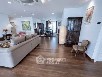 Spacious living room with elegant decor and wooden flooring, featuring a cozy seating area and dining space.