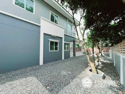 Modern residential building exterior with gravel landscaping and trees