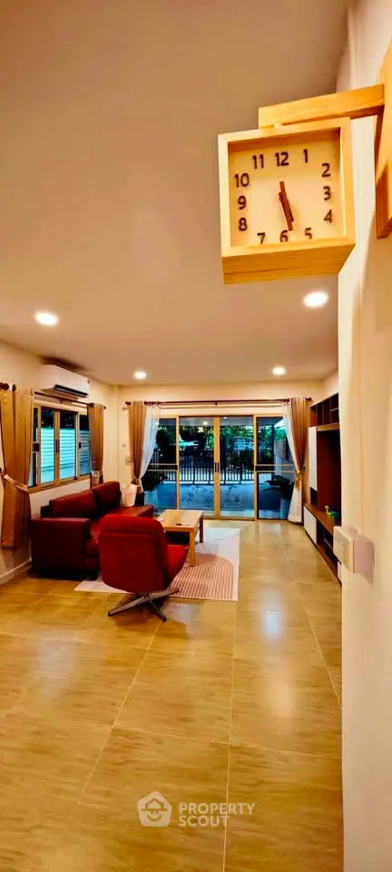 Spacious living room with modern decor and large windows opening to a serene view.