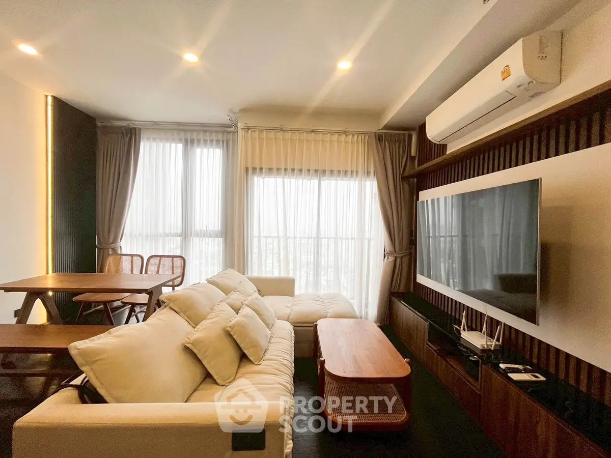 Modern living room with cozy sofa, large TV, and elegant dining area.