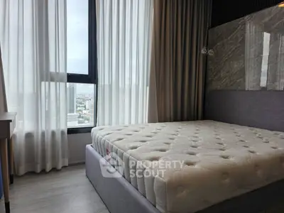 Modern bedroom with large window and city view, featuring a comfortable bed and elegant curtains.