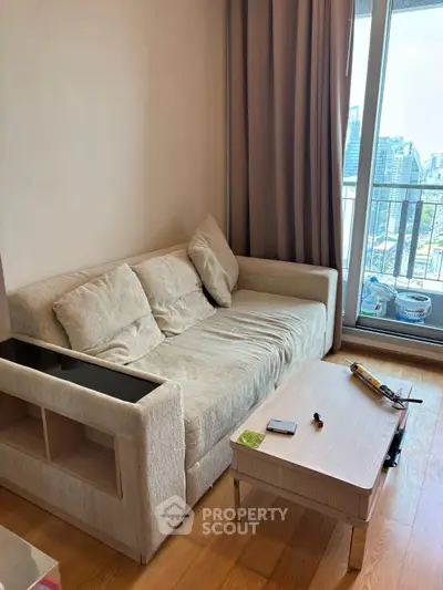 Cozy living room with beige sofa and city view balcony, perfect for relaxation.