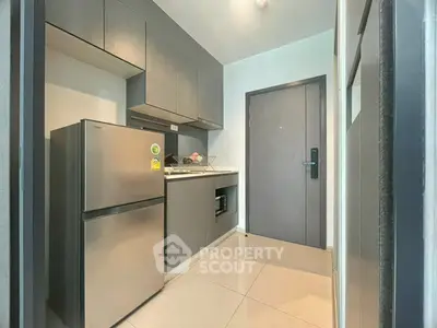 Modern compact kitchen with sleek gray cabinets and stainless steel appliances in a stylish apartment.