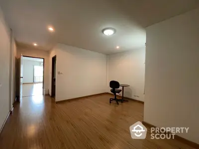 Spacious and well-lit room with gleaming hardwood floors, modern lighting, and a versatile layout ideal for customization in a prime location.