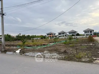 Vacant land with potential for development, surrounded by modern homes and lush greenery, ideal for investment.