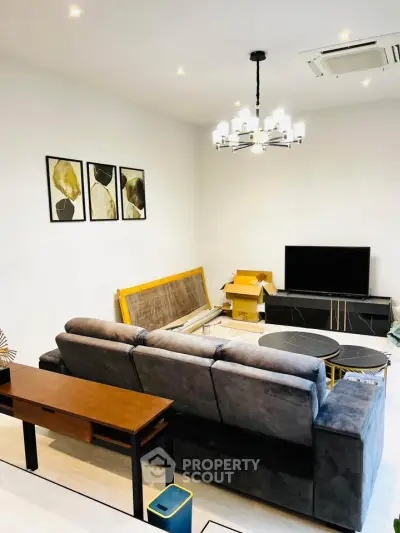 Modern living room with stylish decor and comfortable seating, featuring a sleek TV setup and elegant lighting.