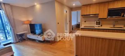 Modern open-layout living room with kitchen, featuring wooden flooring and stylish furniture.