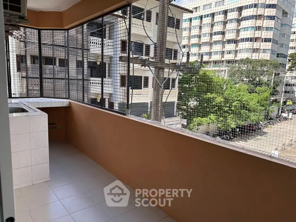 Spacious balcony with safety netting and city view, perfect for relaxation and outdoor activities.