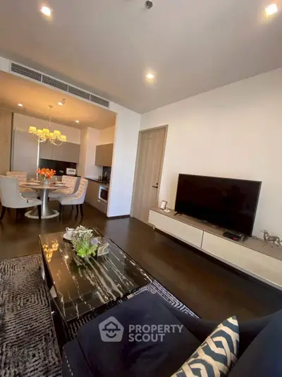 Modern living room with open kitchen, stylish decor, and dining area in a contemporary apartment.