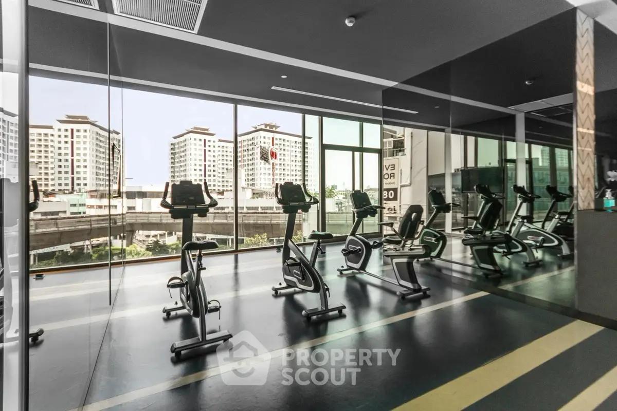 Modern gym with exercise bikes and city view in luxury apartment building.