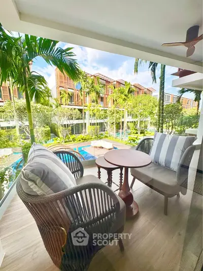 Charming balcony with cozy seating overlooking lush garden and pool in luxury residential complex.