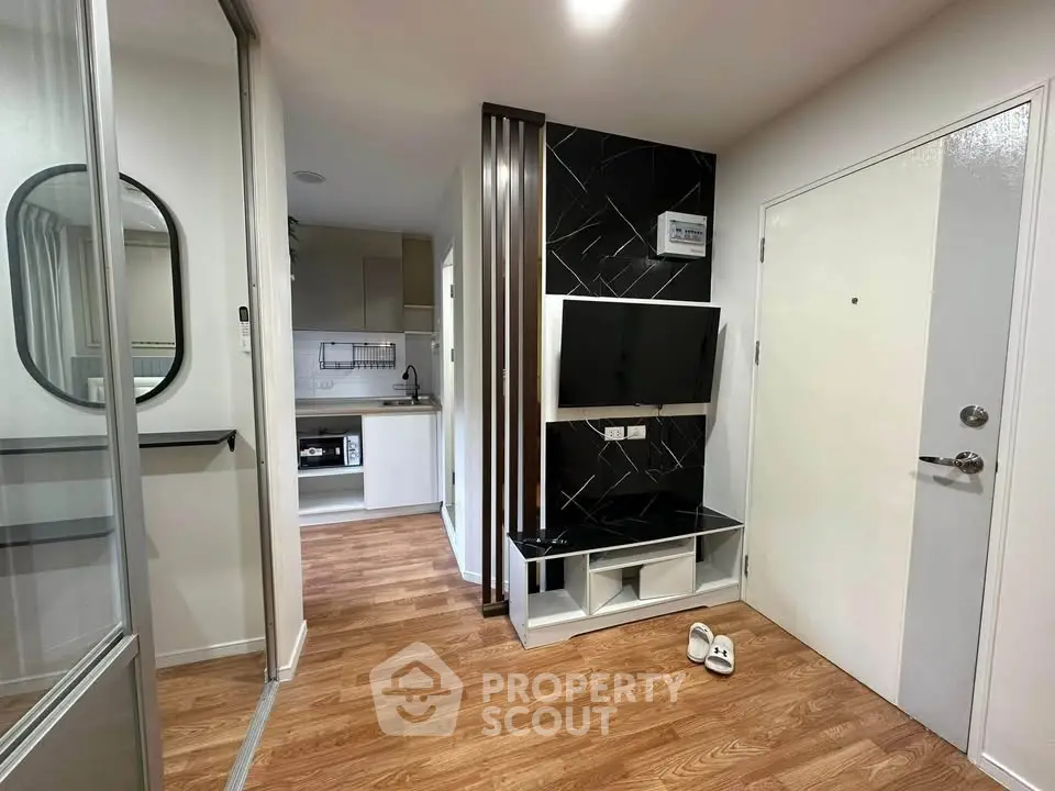 Modern apartment entryway with sleek TV setup and compact kitchen