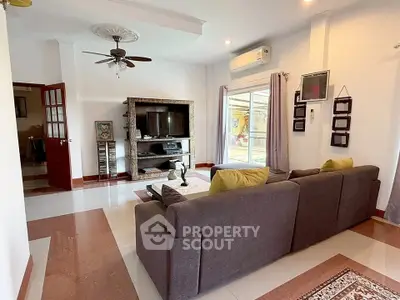 Spacious living room with modern decor and large TV, featuring a cozy sofa and elegant ceiling fan.