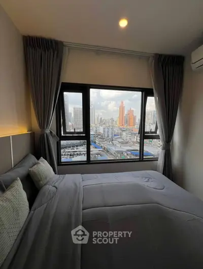 Modern bedroom with city view, featuring large window and elegant decor.