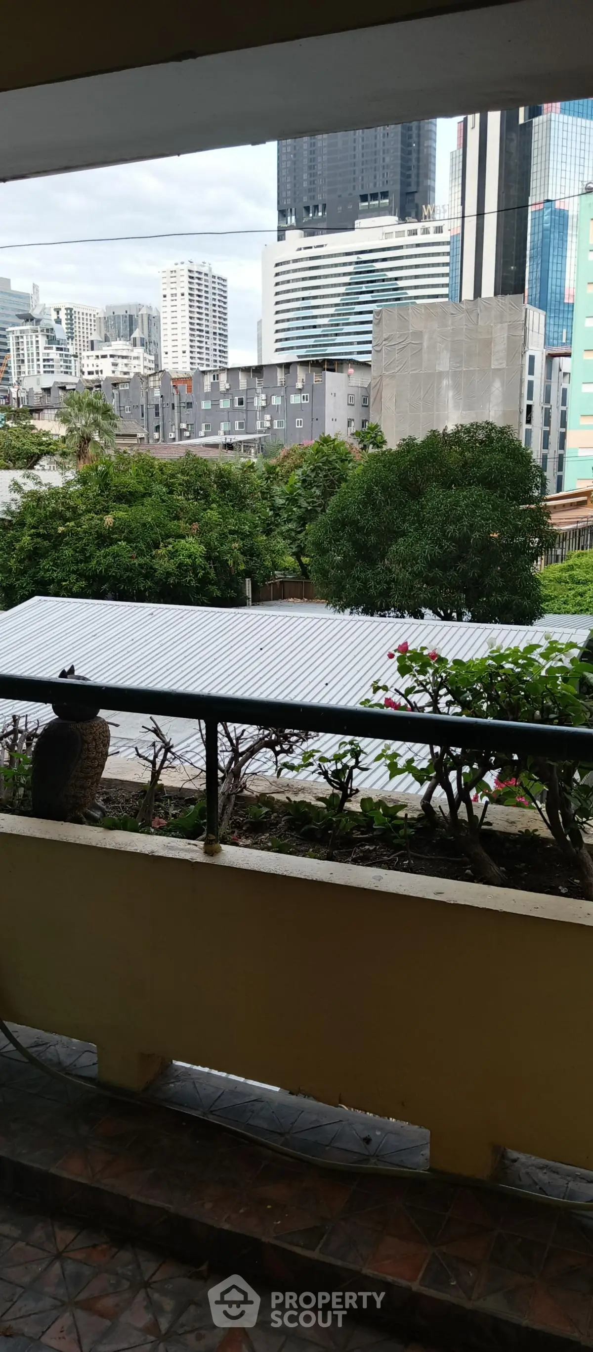 City view from balcony with lush greenery and urban skyline