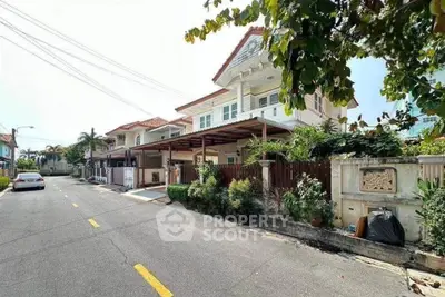 Charming suburban house with lush greenery and spacious driveway on a sunny day.