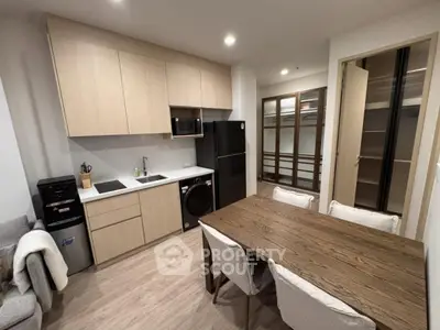 Modern kitchen with sleek cabinetry, dining table, and integrated appliances in a cozy apartment setting.