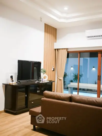 Modern living room with sleek furniture and large sliding glass doors opening to a serene outdoor view.