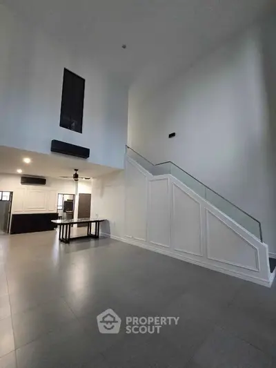 Spacious modern living room with high ceilings and elegant staircase, perfect for contemporary living.
