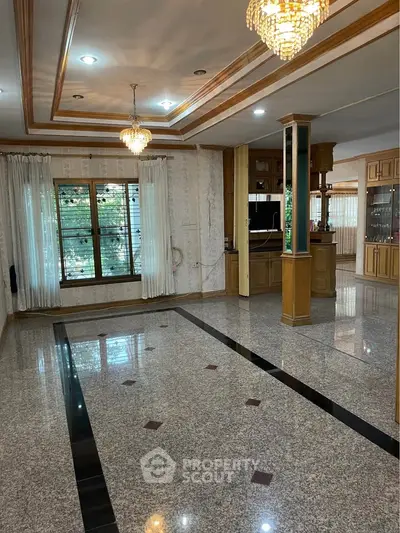 Spacious living room with elegant chandeliers and large windows in a luxurious home.