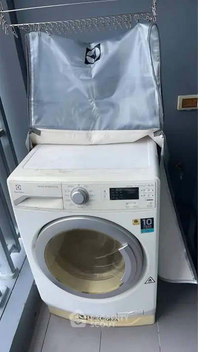 Modern Electrolux washing machine on balcony with protective cover, ideal for urban apartments.