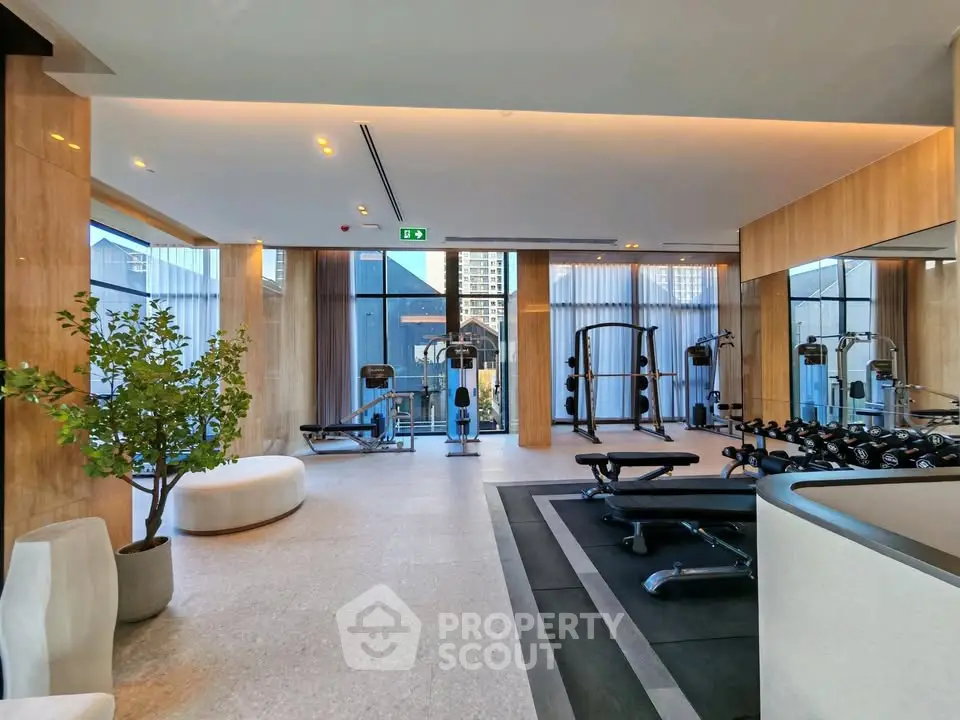 Luxurious gym with modern equipment and city view in upscale residential building.