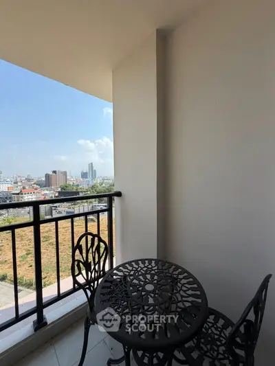 Charming balcony with city view and elegant wrought iron furniture, perfect for relaxation.