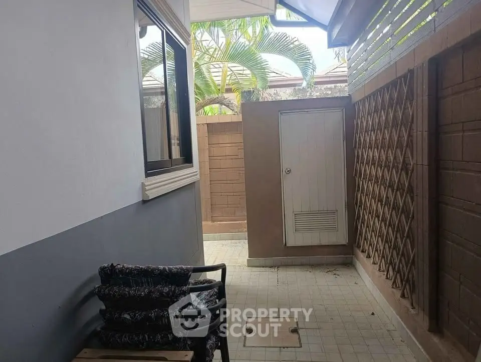 Charming outdoor patio with tropical plants and cozy seating area, perfect for relaxation.