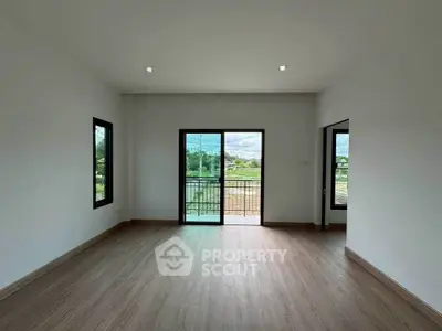 Spacious empty room with large windows and balcony access, offering serene views and abundant natural light.