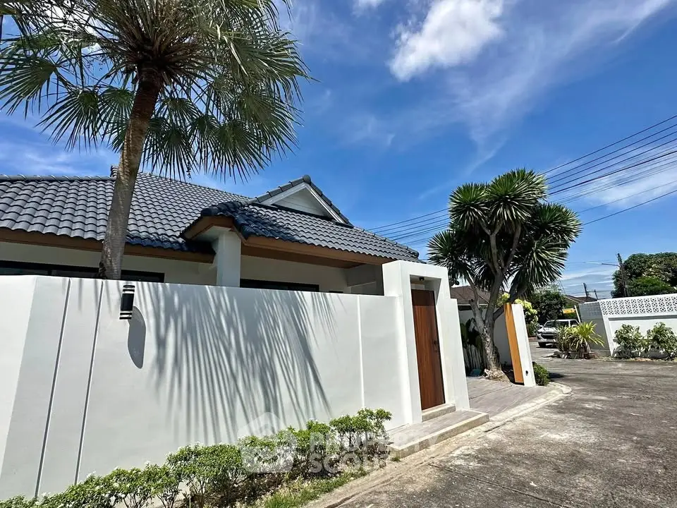 Charming modern house with tiled roof and lush landscaping under a clear blue sky.