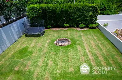 Spacious backyard with lush green lawn and fire pit, perfect for outdoor activities.