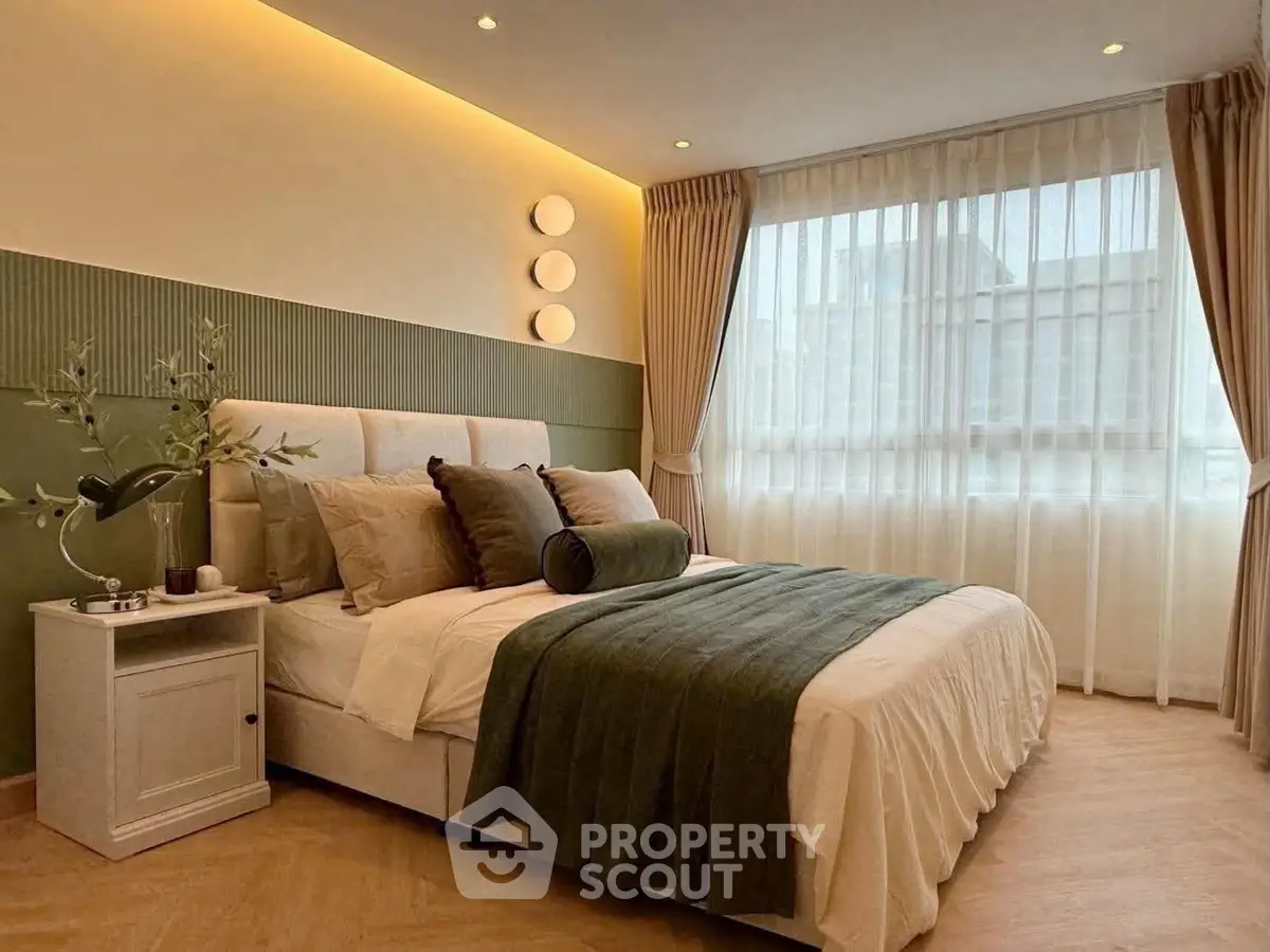 Elegant bedroom with modern decor and large window, featuring stylish lighting and cozy bedding.