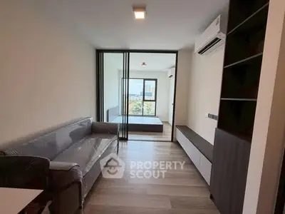 Modern apartment interior with sleek design, featuring a cozy living room and a bedroom with a large window view.