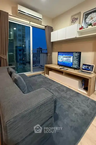 Modern living room with balcony view, featuring sleek furniture and entertainment setup.