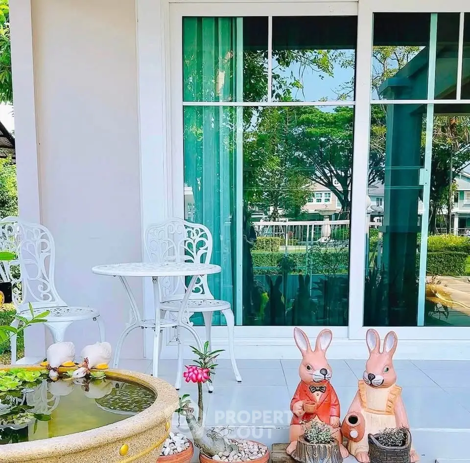 Charming garden patio with elegant white furniture and decorative rabbit statues, perfect for relaxation.