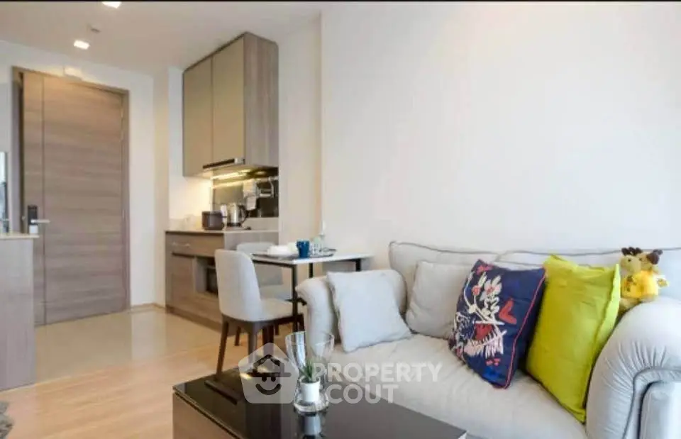 Modern living room with cozy sofa and compact kitchen in open layout apartment.