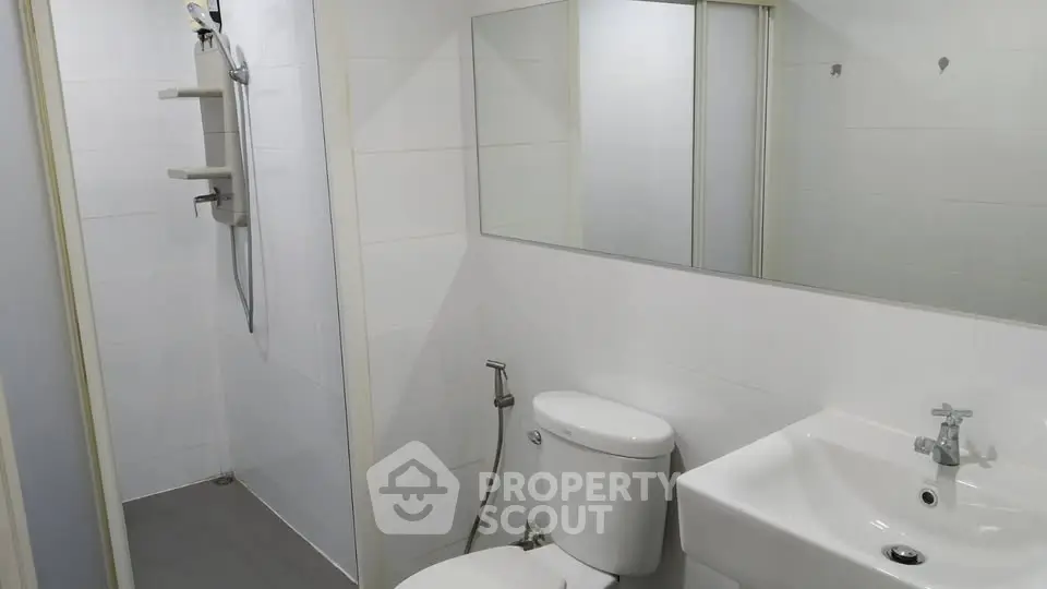 Modern bathroom with sleek white fixtures and spacious shower area.