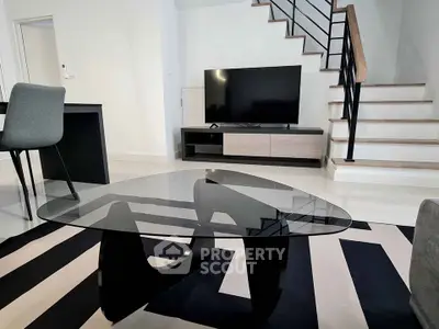 Modern living room with stylish glass coffee table and sleek staircase