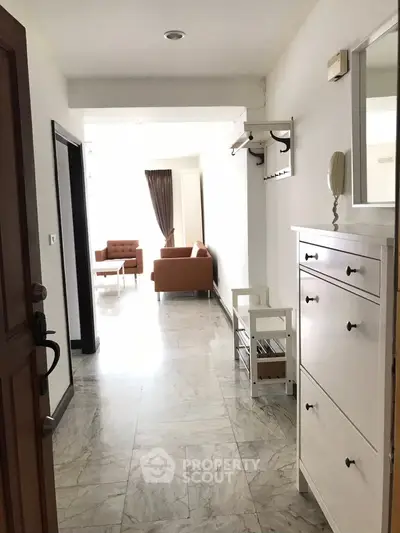 Bright hallway leading to a cozy living room with modern furniture.