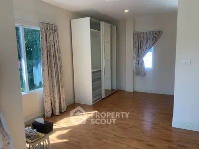 Spacious bedroom with wooden flooring and large windows for natural light.