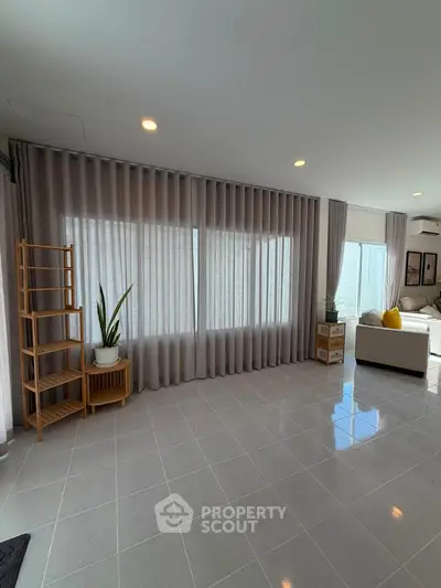 Spacious living room with large windows and modern decor, perfect for relaxation and entertaining.