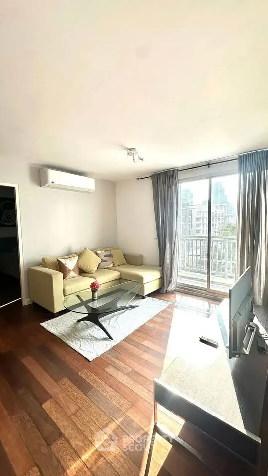 Bright and modern living room with city view, featuring hardwood floors and stylish furniture.