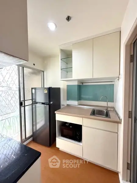 Modern compact kitchen with sleek cabinetry and appliances in a bright apartment.