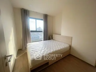 Bright bedroom with large window and city view, featuring a comfortable bed and modern decor.