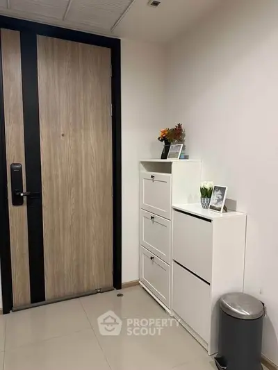 Modern apartment entrance with sleek wooden door and stylish white storage cabinets.